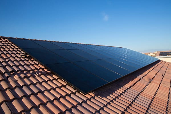 View of black solar panels on a tile roof on a sunny day