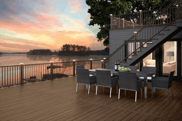 Sunset with view of bay and deck with solar post lights glowing