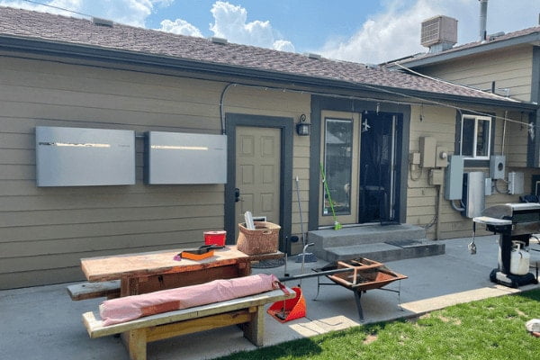 A home with an Enphase Encharge battery system on the wall in the backyard